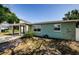 Side view of the house featuring a covered carport and tidy landscaping against a blue sky at 3216 W Paxton Ave, Tampa, FL 33611