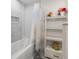 Bright bathroom featuring tub/shower combo with white decorative tiles and shelving for storage and decor at 3407 W Busch Blvd, Tampa, FL 33618