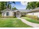 Charming single-story home featuring a brick walkway, manicured lawn, and lush landscaping at 3407 W Busch Blvd, Tampa, FL 33618