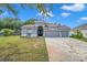 This single-story home boasts a three-car garage and manicured front lawn beneath a bright blue sky at 3527 101St E Ave, Parrish, FL 34219