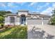 Charming single-Gathering home features a three-car garage, landscaped lawn, and stylish blue double-door entry at 3527 101St E Ave, Parrish, FL 34219