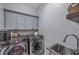 This laundry room has new, front-loading washer and dryer units, a sink, and cabinets at 3527 101St E Ave, Parrish, FL 34219