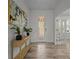 Bright hallway with wood-look floors, console table with plants, and a view of the front door with decorative glass at 4528 Ballantrae Blvd, Land O Lakes, FL 34638
