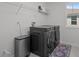 Modern laundry room with front load washer and dryer, shelving, and stylish rug at 4528 Ballantrae Blvd, Land O Lakes, FL 34638