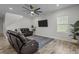 Spacious living room featuring wood floors, ceiling fan, flatscreen TV, and comfortable leather seating at 4528 Ballantrae Blvd, Land O Lakes, FL 34638