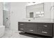 Bathroom featuring a gray vanity with marble countertop and a framed mirror, complemented by a shower with marble tile at 5009 W Longfellow Ave, Tampa, FL 33629