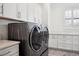 Contemporary laundry room featuring a front-load washer and dryer, white cabinets, and a countertop for folding and sorting laundry at 5009 W Longfellow Ave, Tampa, FL 33629