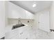 Laundry room featuring white cabinets, a stainless steel sink, marble floors and a door to the exterior at 501 Sportsman Park Dr, Seffner, FL 33584