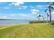 Lovely condo backyard with a grassy lawn that meets the water with bridge views and palm trees on a sunny day at 6357 Bahia Del Mar Blvd # 111, St Petersburg, FL 33715