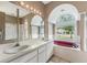 Luxurious bathroom featuring double sinks, custom mirror lighting, a tub and an arched window at 7039 Woodibis Dr, New Port Richey, FL 34654
