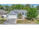Inviting single-story home with blue trim, a two-car garage, and a neatly landscaped front yard at 7039 Woodibis Dr, New Port Richey, FL 34654