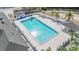 Aerial shot of a community pool with colorful flags, umbrellas, lounge chairs and mature landscaping at 7039 Woodibis Dr, New Port Richey, FL 34654