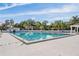 Bright swimming pool enclosed by a white fence, surrounded by lush greenery and a clear blue sky at 7039 Woodibis Dr, New Port Richey, FL 34654