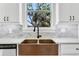 Close-up of a copper kitchen sink with white cabinets and a window view of lush trees at 7113 S Kissimmee St, Tampa, FL 33616