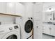Laundry room with white washer and dryer and storage cabinets; view into bathroom at 7113 S Kissimmee St, Tampa, FL 33616