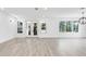 Spacious living room with light wood-look floors, leading to a balcony and surrounded by greenery at 7113 S Kissimmee St, Tampa, FL 33616