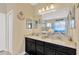 Elegant double vanity bathroom with granite countertops, dark cabinets, and well-lit mirrors at 7502 Sea Lilly Ct, Apollo Beach, FL 33572