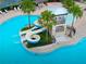 Stunning aerial view of a pool with a slide and tower, surrounded by palm trees and turquoise water at 7502 Sea Lilly Ct, Apollo Beach, FL 33572