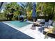 Beautiful backyard pool features stone tiling, blue umbrellas, and outdoor lounge furniture for relaxing at 865 Live Oak Ne Ter, St Petersburg, FL 33703