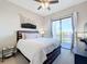Cozy bedroom featuring a ceiling fan and sliding glass doors leading to a balcony with water views at 949 Symphony Isles Blvd, Apollo Beach, FL 33572