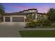 Elegant stucco home featuring a tile roof, three-car garage, paver driveway, and meticulously manicured landscaping at 949 Symphony Isles Blvd, Apollo Beach, FL 33572