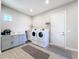 Well-lit laundry room with gray cabinetry, shelving, washer and dryer, and decorative rug at 949 Symphony Isles Blvd, Apollo Beach, FL 33572