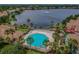 Aerial view of a community pool, palm trees, and a lake with a fountain at 9828 Lake Chase Island Way # 0, Tampa, FL 33626