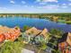 Stunning aerial view of waterfront townhomes, lush landscaping, and a serene lake reflecting the clear blue sky at 9828 Lake Chase Island Way # 0, Tampa, FL 33626