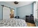 Bright bedroom with blue walls, wood floors, ceiling fan, and barn door to bathroom at 9828 Lake Chase Island Way # 0, Tampa, FL 33626
