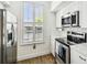 Well-lit kitchen featuring stainless steel appliances, white cabinets, and wood-look flooring at 9828 Lake Chase Island Way # 0, Tampa, FL 33626