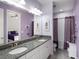 A modern bathroom features double sinks with granite countertops and stylish purple accents at 10450 Highland Park Pl, Palmetto, FL 34221
