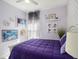 A charming bedroom features soft lavender walls and a plush purple comforter, creating a cozy and inviting retreat at 10450 Highland Park Pl, Palmetto, FL 34221