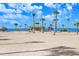 Sandy beach with beach house, palm trees, and a beautiful blue sky at 1134 Starfish Ln, Tarpon Springs, FL 34689