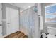Bright bathroom with a shower featuring stylish blue-patterned curtains and wood-look floors at 12908 Hawkstone Trail Blvd, Lithia, FL 33547