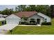 Exterior of the home featuring manicured lawn, driveway, two-car garage, covered entryway, and well-kept shrubs at 13486 English Sparrow Rd, Weeki Wachee, FL 34614