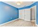 Bedroom with blue walls, wood-look floors, and large closet with white doors at 2719 Brookville Dr, Valrico, FL 33596