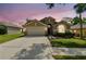 Charming single-story home featuring a two-car garage, well-manicured lawn, and mature landscaping at sunset at 2719 Brookville Dr, Valrico, FL 33596