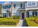 Inviting townhome with a striking red front door, surrounded by lush landscaping and well-maintained greenery at 309 Countryside Key Blvd, Oldsmar, FL 34677