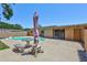 Backyard view with concrete patio, freeform pool, table with umbrella, and partial fence line at 403 Cactus Cir, Seffner, FL 33584