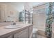 Bright bathroom with a white vanity, patterned wallpaper, and a shower with a decorative floral curtain at 417 Ventura Dr, Oldsmar, FL 34677