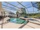Enclosed pool and hot tub area featuring a screen enclosure, shed and a blue patio set at 417 Ventura Dr, Oldsmar, FL 34677