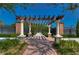 Picturesque arbor entrance with brick columns, stone accents, and walkway leading to tennis courts at 4289 Ortona Ln, Wesley Chapel, FL 33543