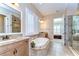 Bright bathroom with a soaking tub, walk-in shower, double granite vanity, and access to the main bedroom at 4289 Ortona Ln, Wesley Chapel, FL 33543