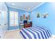Vibrant blue bedroom with a striped bed, white trim, an animal-themed picture set, and a window with shutters at 4289 Ortona Ln, Wesley Chapel, FL 33543