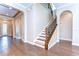 Open foyer with hardwood floors, staircase, and arched doorway at 4289 Ortona Ln, Wesley Chapel, FL 33543