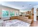 Open floorplan with hardwood floors, a sectional sofa, kitchen, and dining area at 4289 Ortona Ln, Wesley Chapel, FL 33543