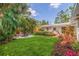 Expansive backyard boasts lush green grass, a fire pit, and tropical landscaping, perfect for outdoor entertaining at 4340 Narvarez S Way, St Petersburg, FL 33712