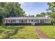 Charming single-story home with lush green lawn, manicured hedges, and inviting front porch at 4340 Narvarez S Way, St Petersburg, FL 33712
