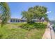 Well-maintained lawn with a large tree, canal views, and a glimpse of the home's patio and pool area at 4433 38Th S Way, St Petersburg, FL 33711