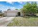 Charming single-story home featuring a two-car garage, arched entryway, and mature landscaping under a sunny sky at 5263 Kirkwood Ave, Spring Hill, FL 34608